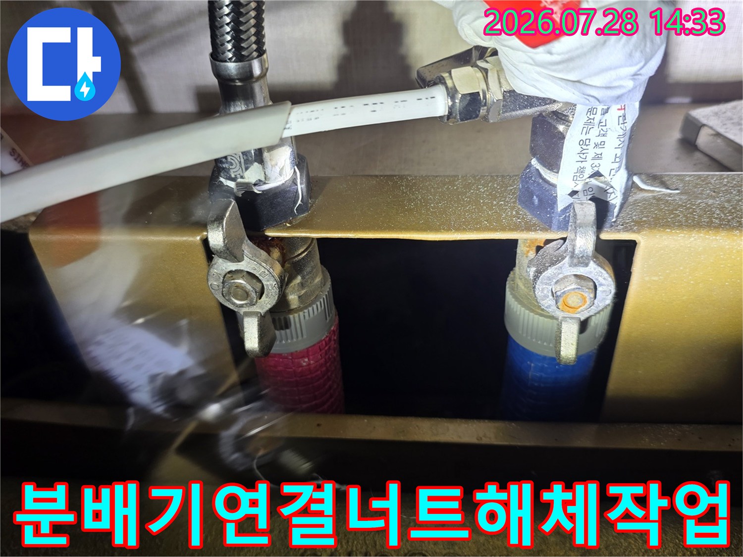 싱크대-하단-금속-프레임-위의-배관-분배기와-공구를-사용해-작업하는-장면