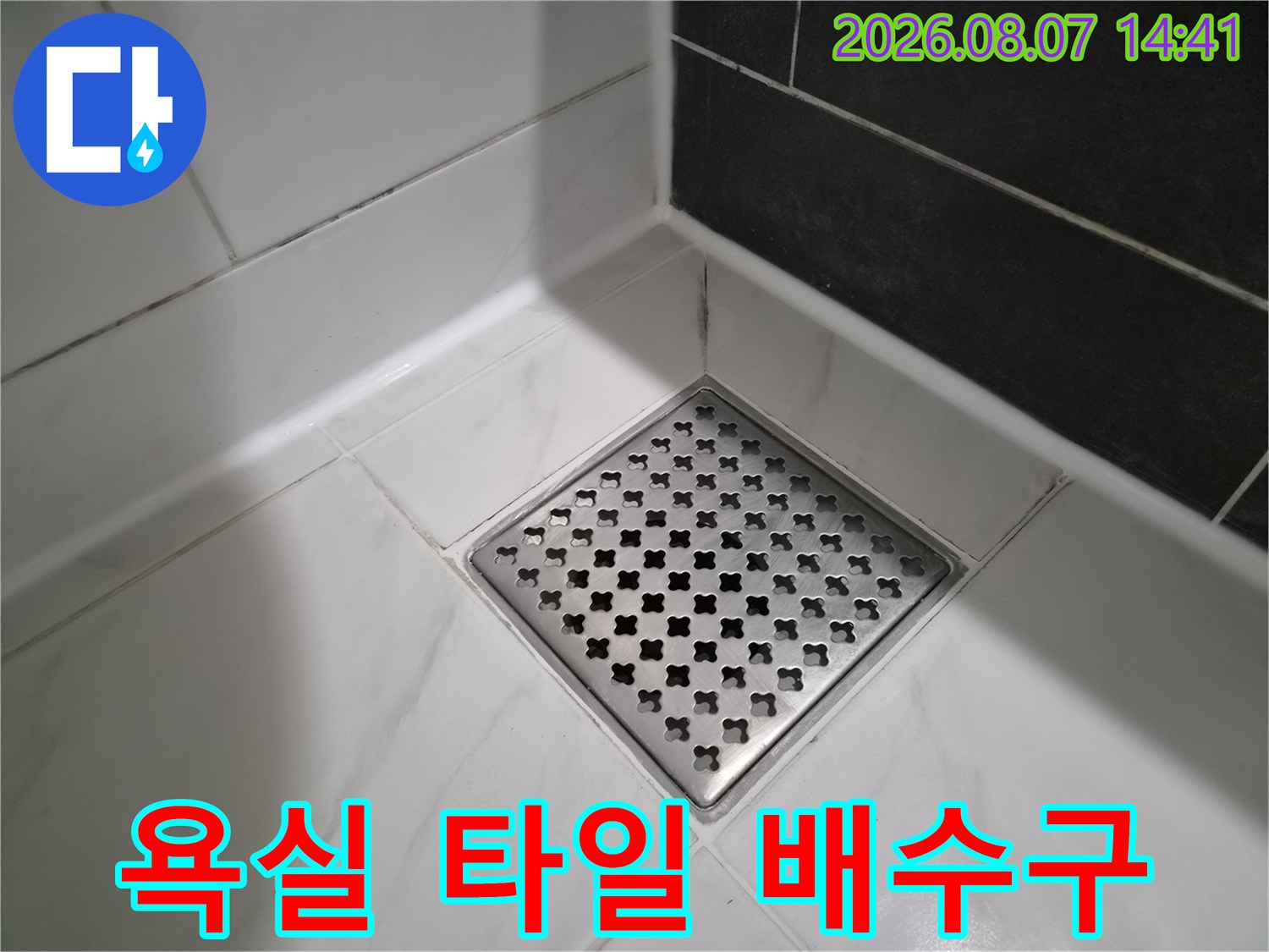 밝은색 대리석 패턴 타일과 금속 배수구의 모습