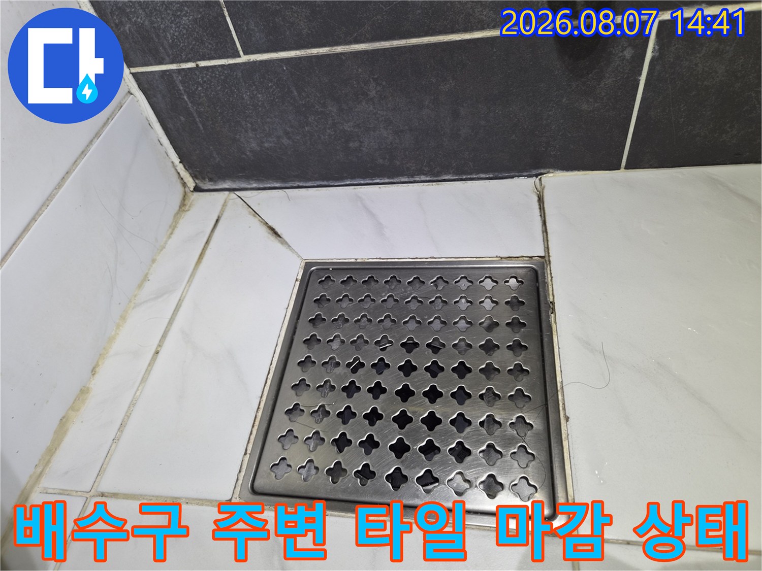 스테인리스 배수구 덮개와 흰색 욕실 타일의 경계면 사진
