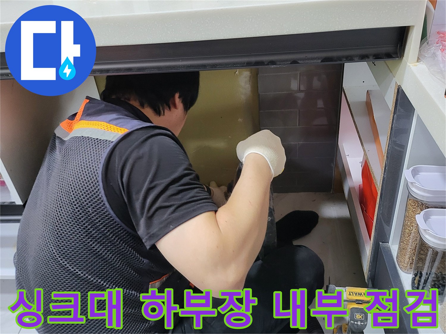 좁은 싱크대 밑 공간에서 배관 상태를 면밀히 조사하는 모습