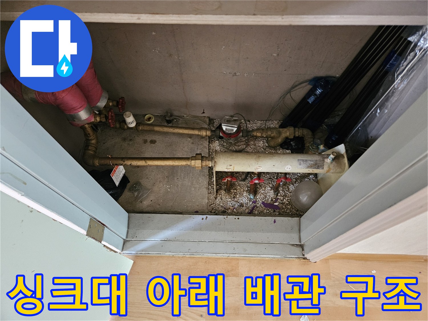 복잡하게 얽힌 주방 하부장 내부의 금속 및 보온재 배관