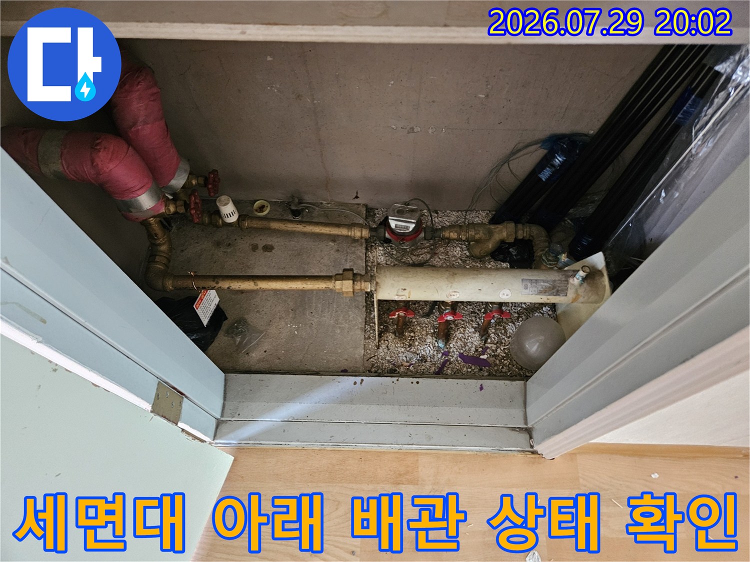 세면대 하부 공간에서 노출된 수도 및 온수 배관을 상세히 진단하는 장면