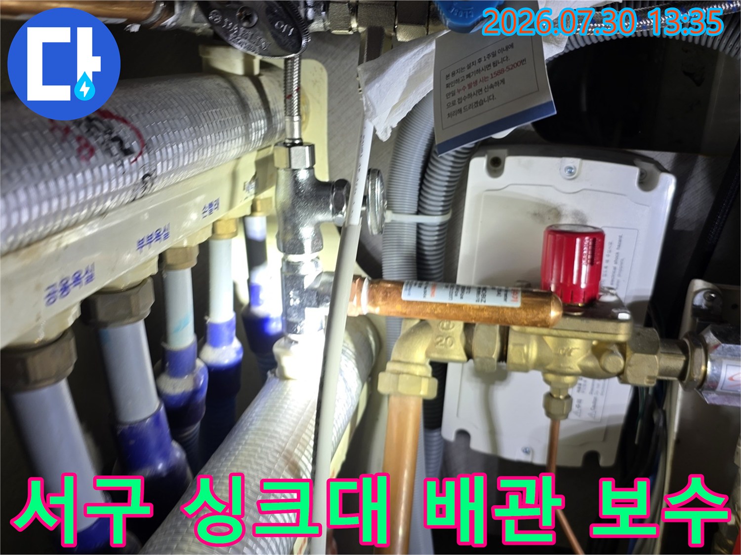 싱크대 아래 설치된 온수 분배기의 밸브 연결부 수선 작업 사진