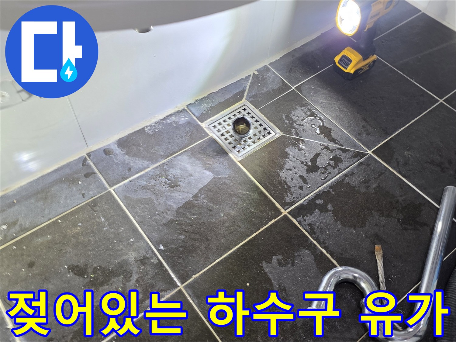물기가 남아있는 - 화장실 배수구와 주변 타일의 모습