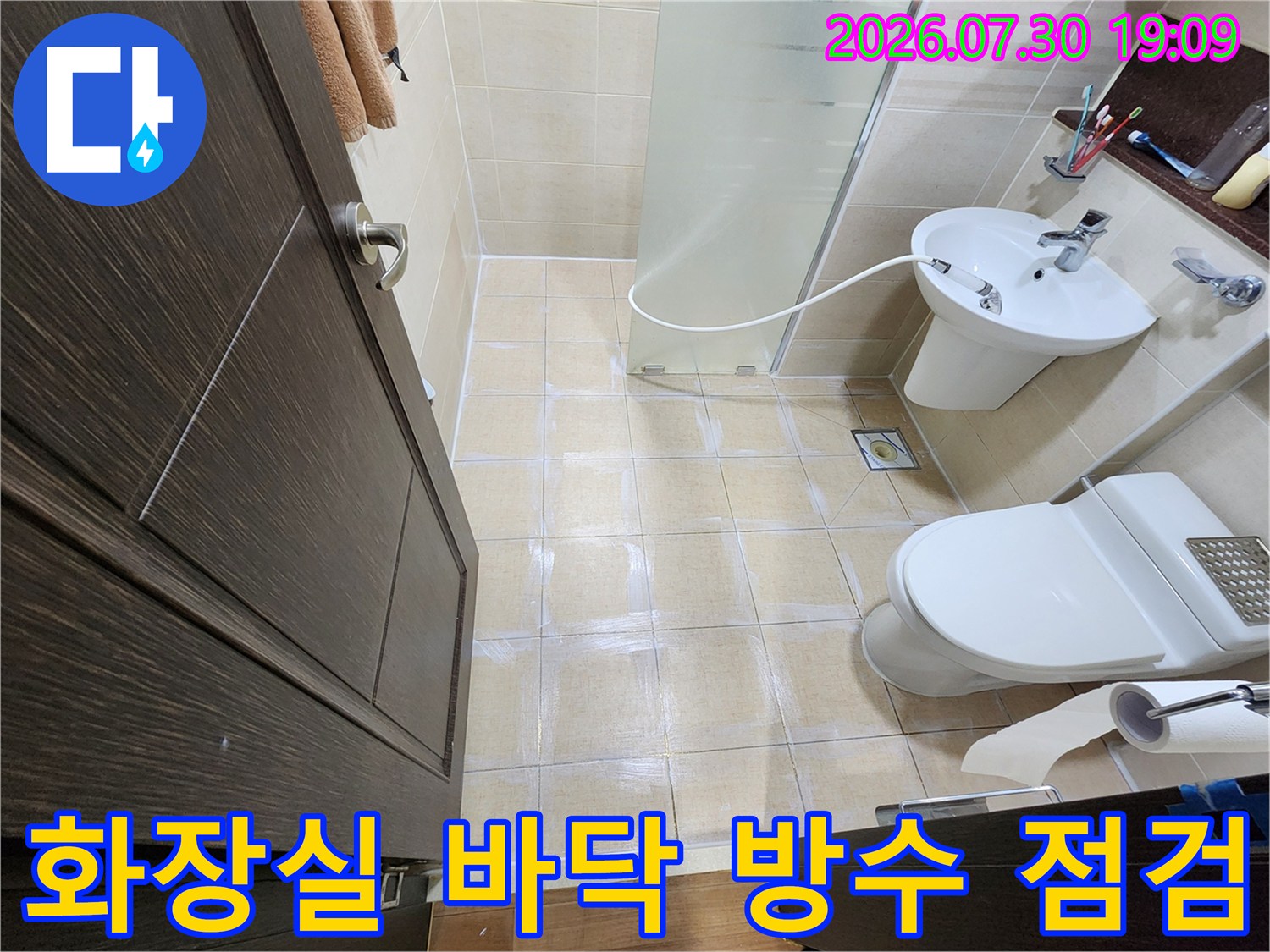 변기와 세면대가 설치된 화장실 내부를 촬영한 사진