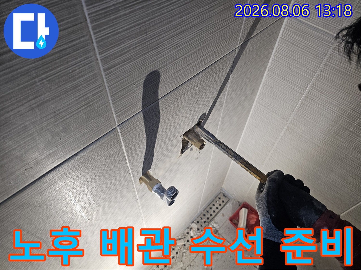 수전 연결부의 노출된 배관을 점검하며 수선 계획을 세우는 기술자의 모습