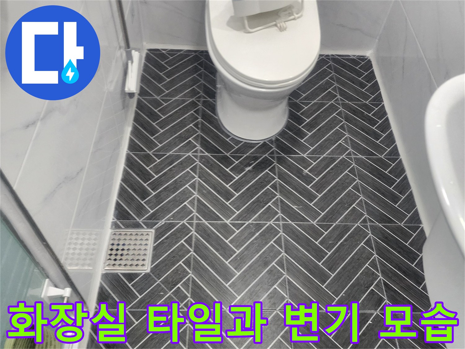 헤링보른-패턴의-어두운-타일과-하얀색-변기가-있는-욕실-바tes