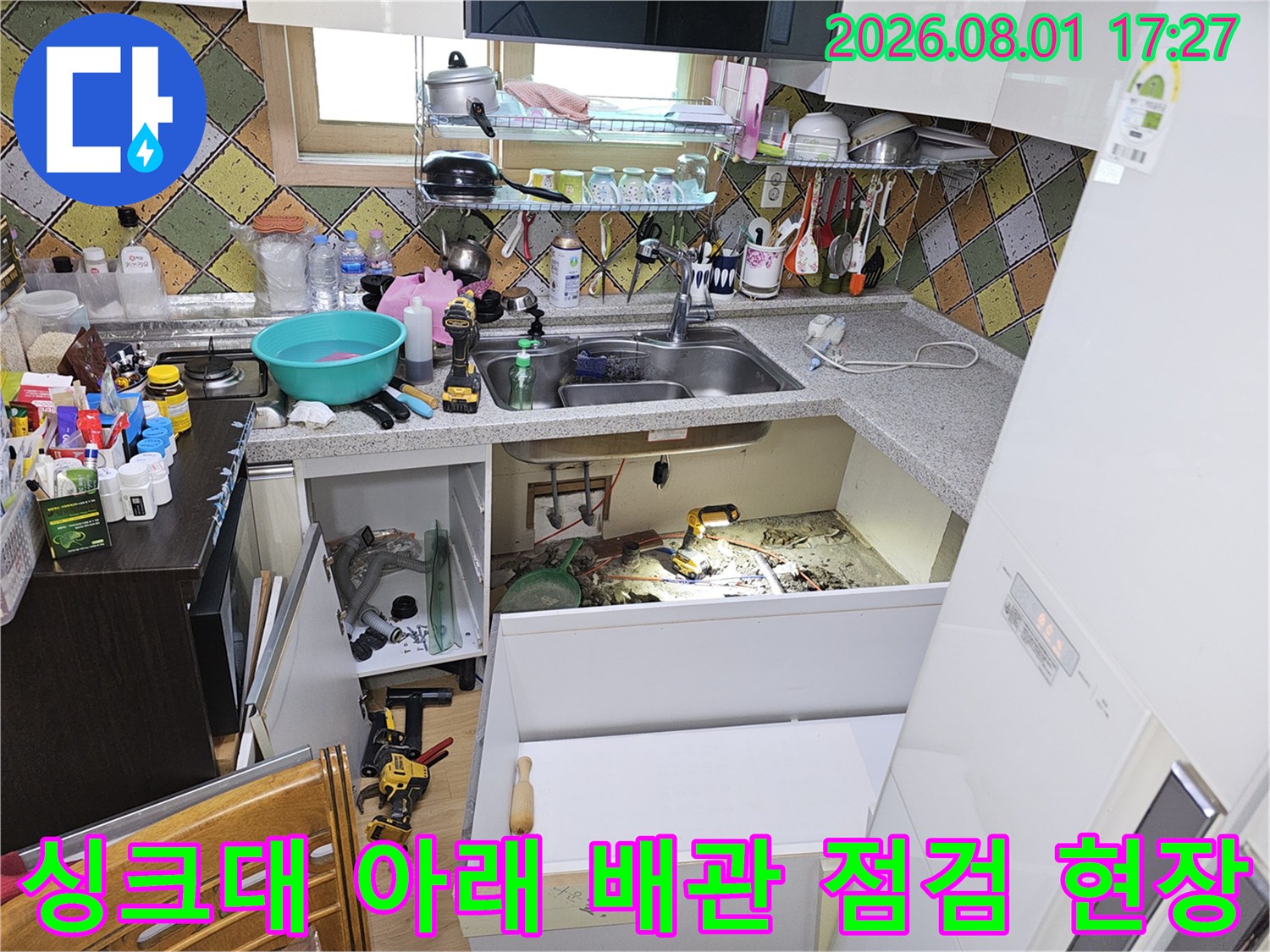 싱크대 밑에서 수전과 연결된 배관의 이상 유무를 확인하는 작업 모습