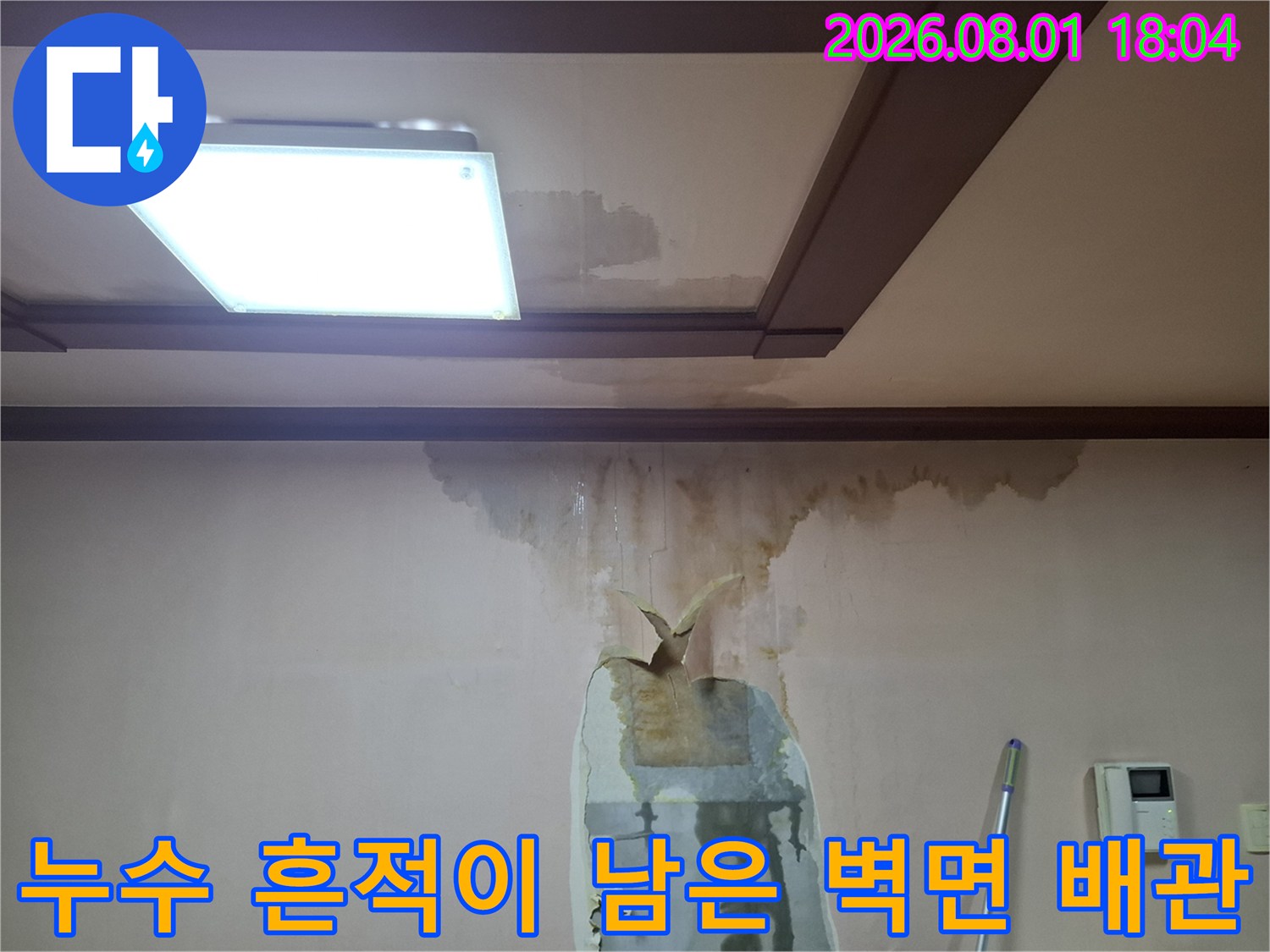 천장과 벽면이 만나는 지점의 누수 얼룩 및 배관 노출 부위