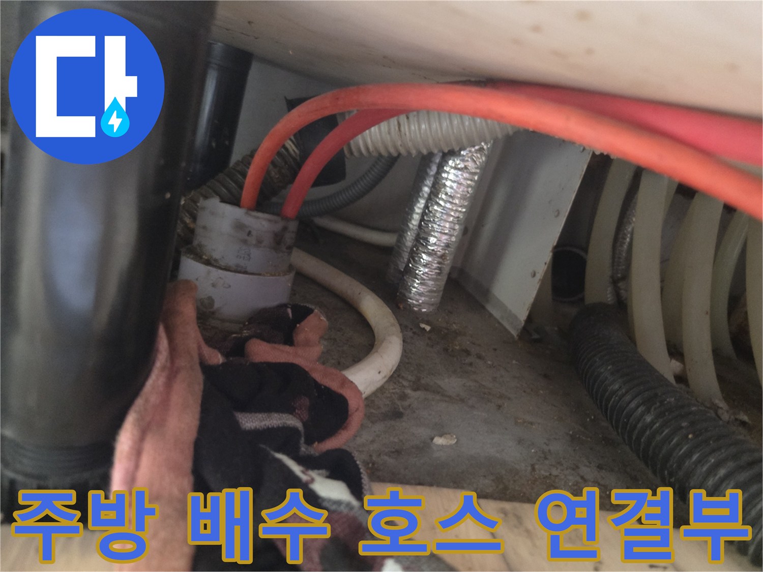 싱크대 아래쪽 배수 호스와 은색 자재가 보이는 현장 사진