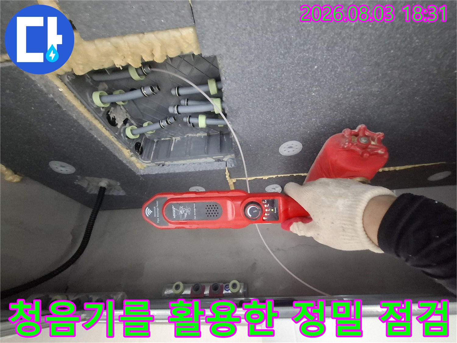 전문가가 장갑을 끼고 청음기로 화장실 천장 배관의 이상 유무를 파악하는 장면