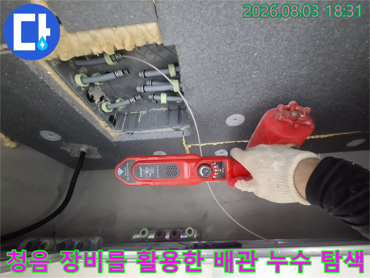 화장실 천장 내부의 복잡한 구조 속에서 청음 탐지기로 문제의 수도배관 위치를 정확히 파악하는 모습