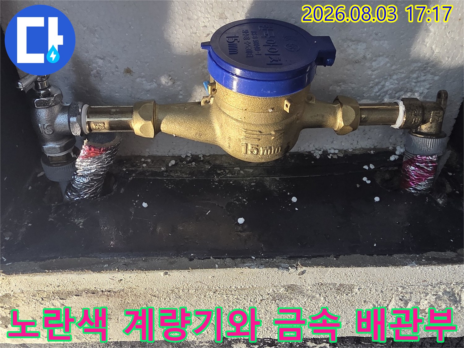 금속 관과 노란색 계량기가 결합된 배관 구조