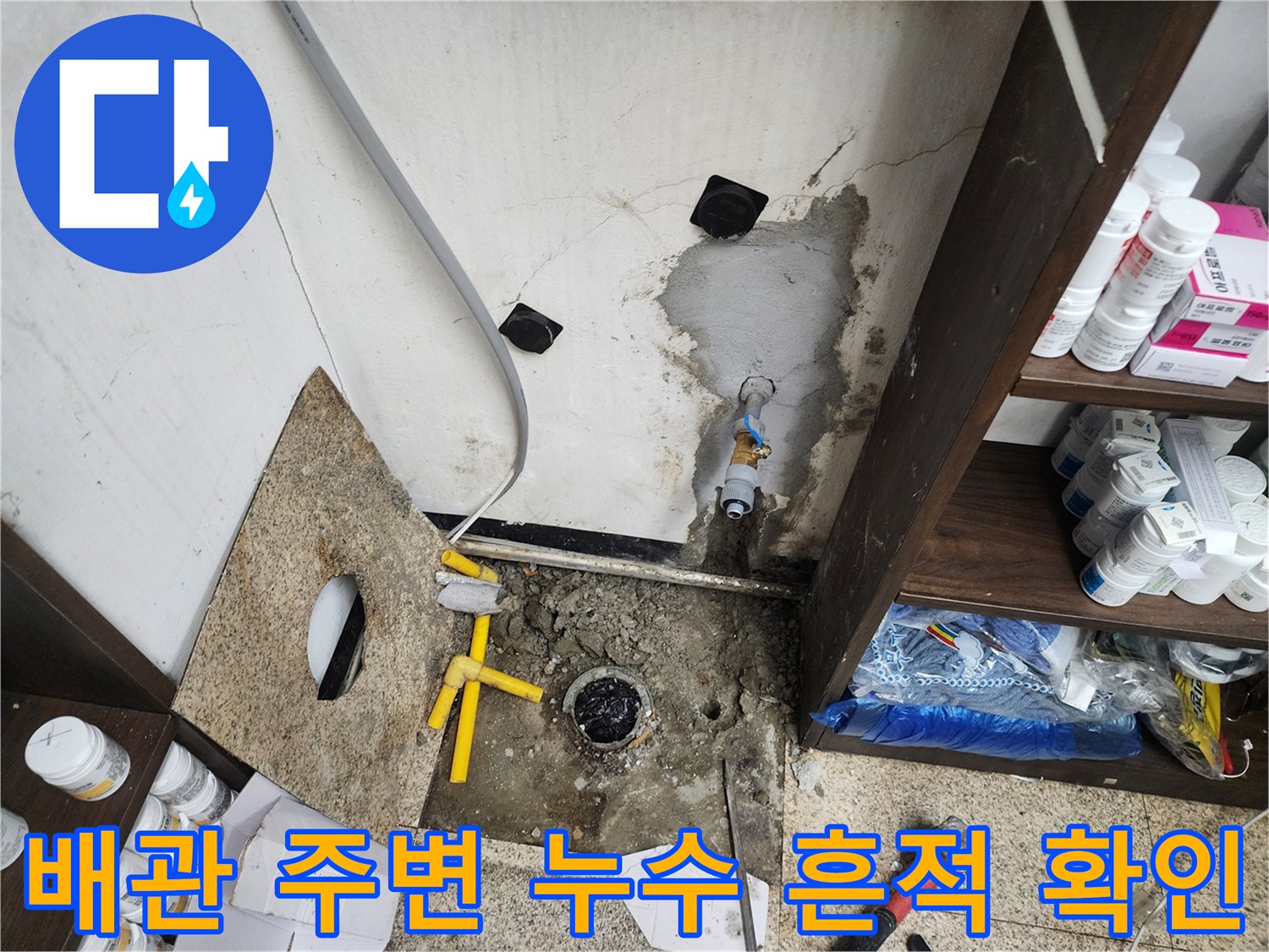 싱크대 하부의 젖은 바닥과 벽면 배관 연결 부위 모습