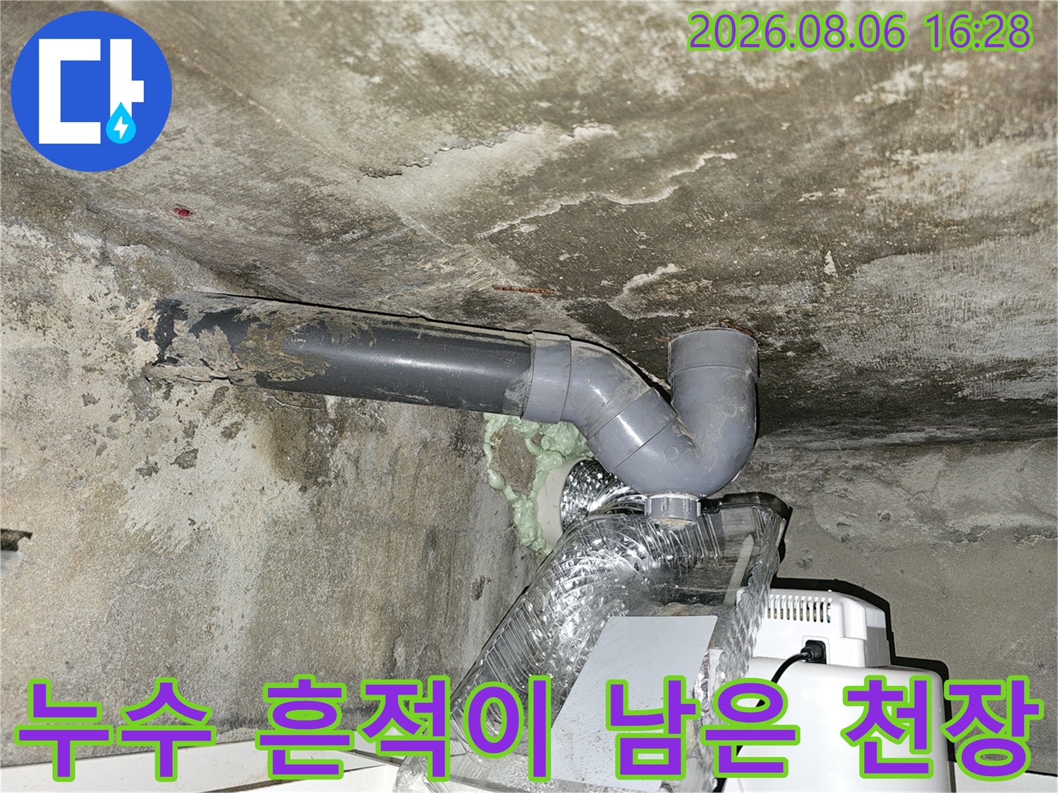습기로 인해 얼룩진 콘크리트 천장과 PVC 배관 연결부