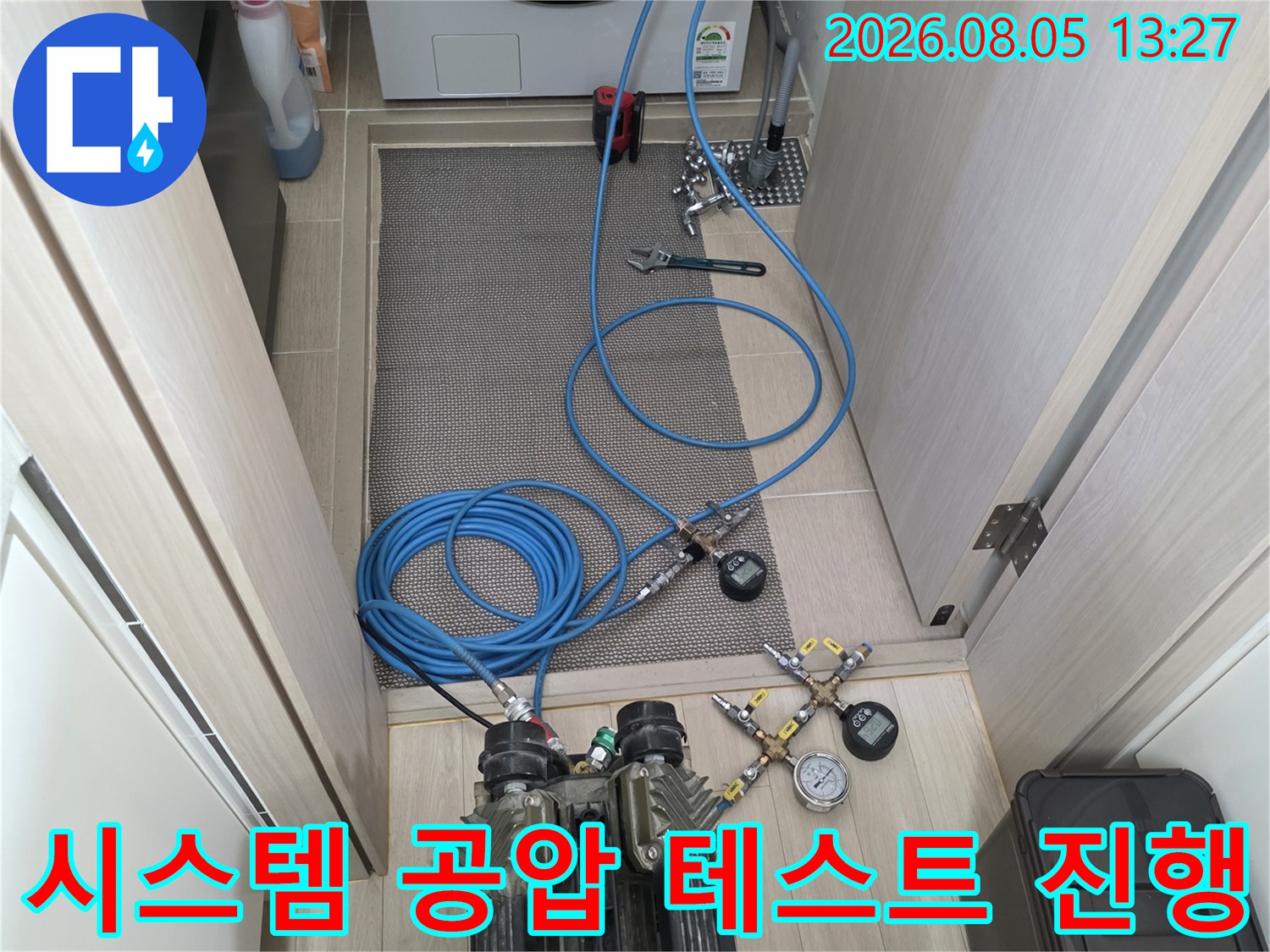 전문가용 압력 게이지와 파란색 배관 호스를 이용한 누수 정밀 점검 장면