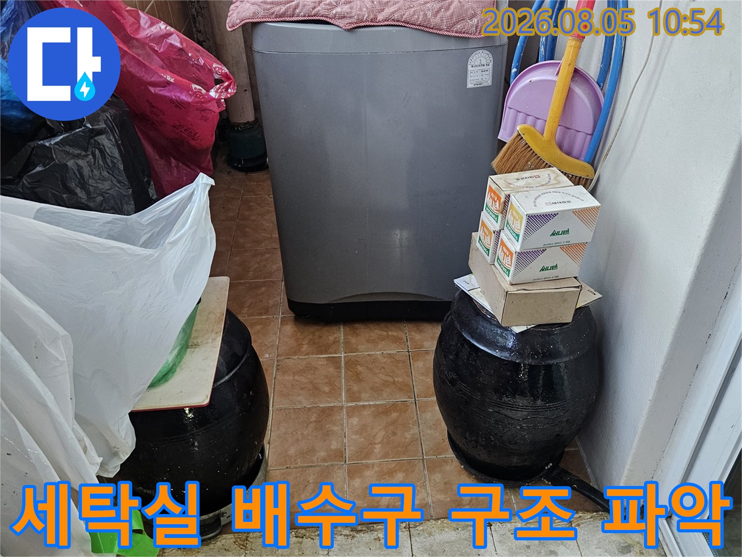 호스가 겹쳐진 세탁기 주변의 노출된 배출부와 시설물