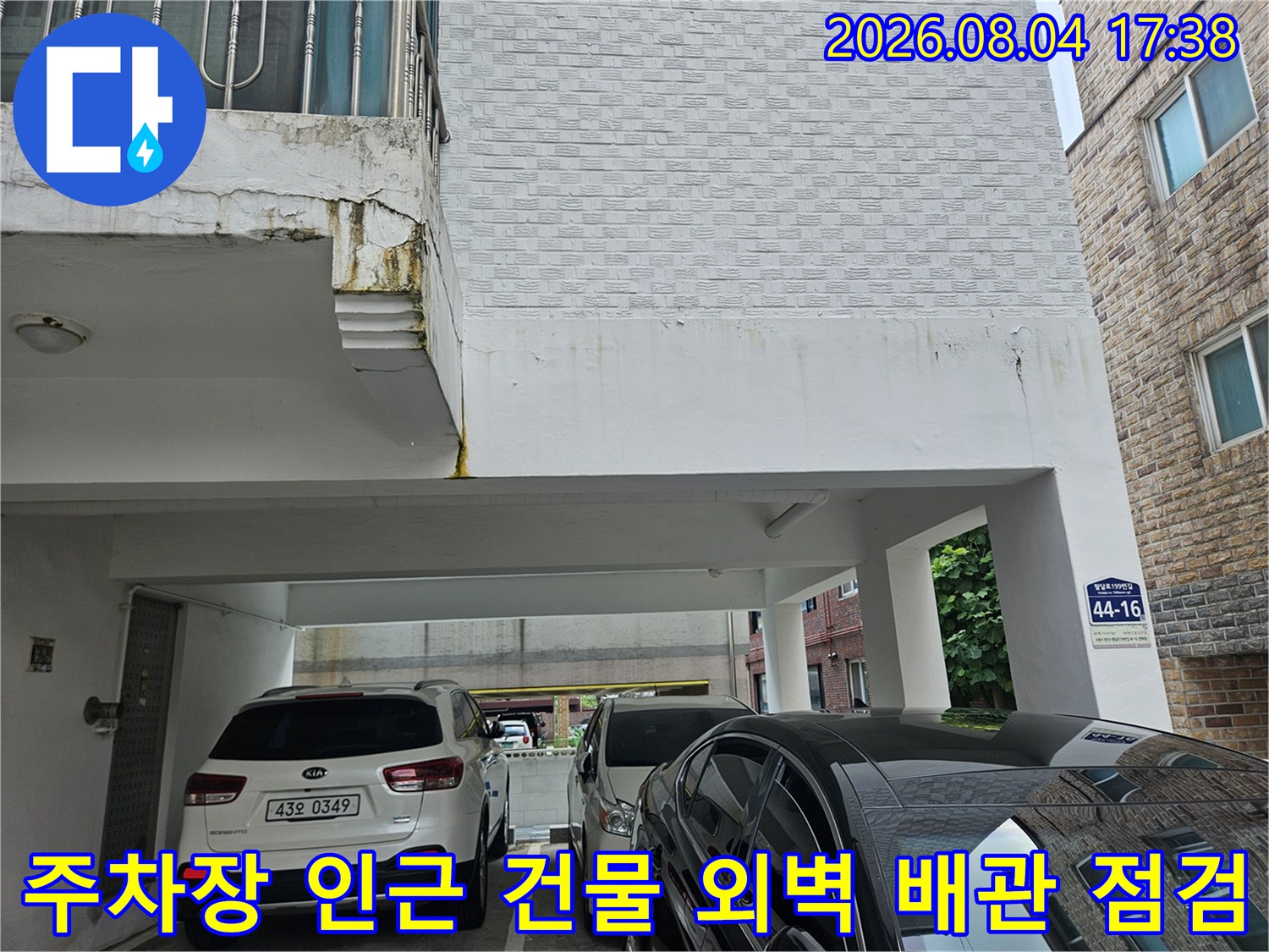 건물 외벽과 주차장이 보이는 공간에서 진행되는 누수 공사 현장