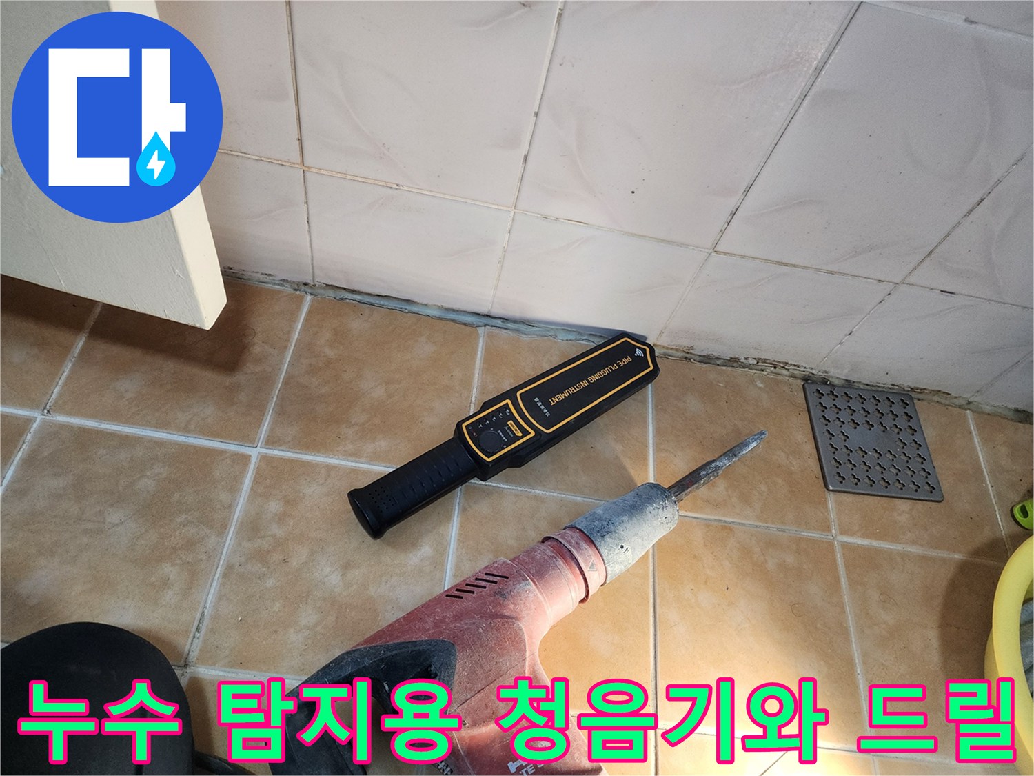 바닥 타일 옆에 놓인 배관 검사 장비와 작업 도구