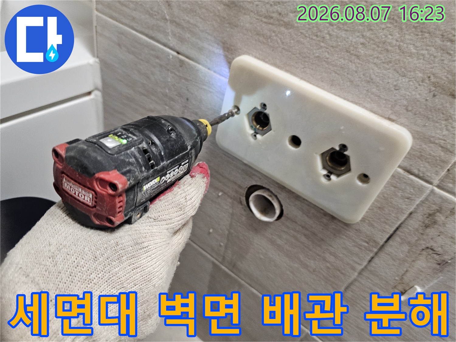 드릴을 사용하여 세면대 벽면 수전 부속을 제거하는 공사 장면