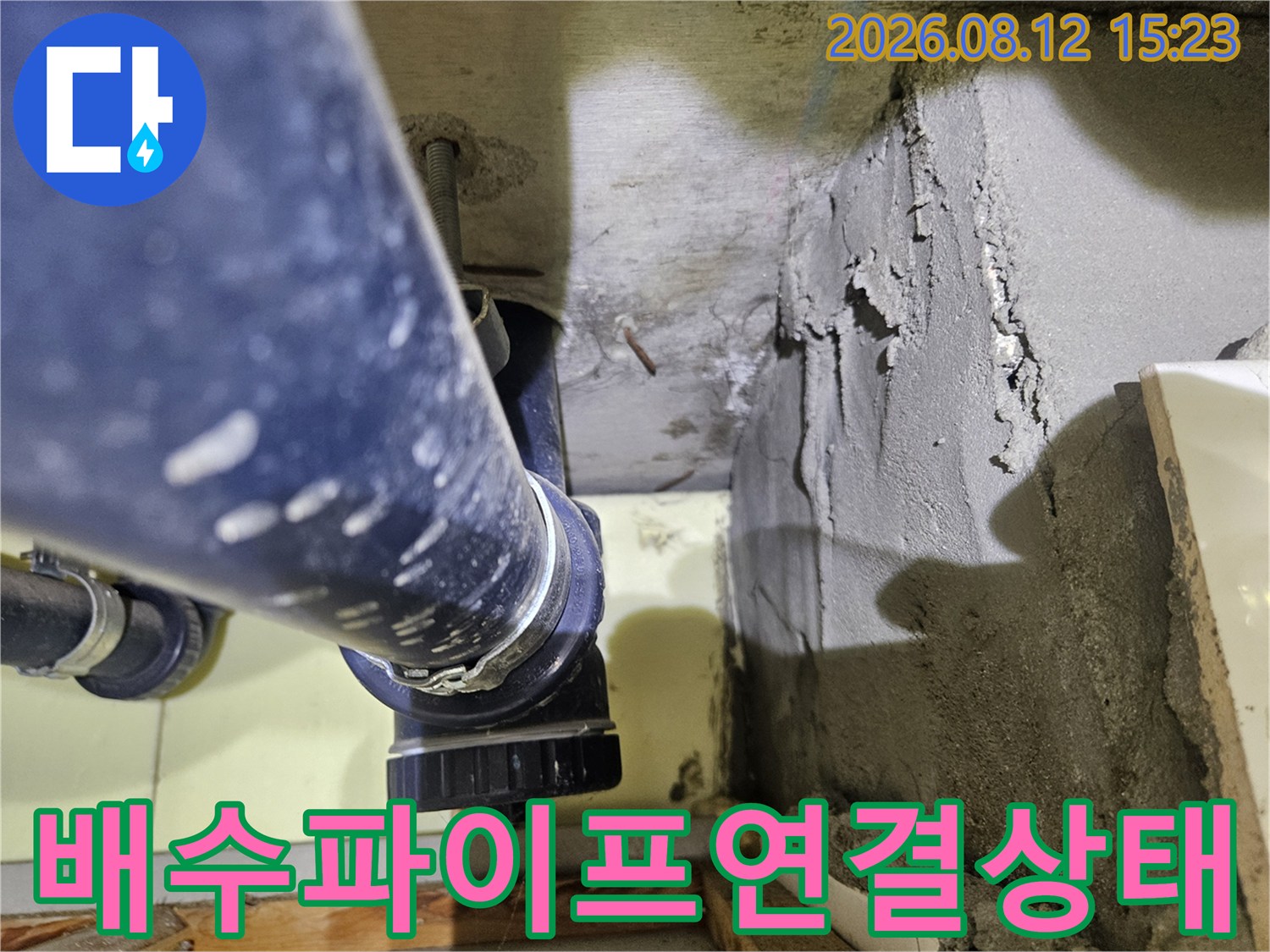 화장실 천장 내부에 설치된-파란색 배수 파이프와 거친 시멘트 벽면의 모습