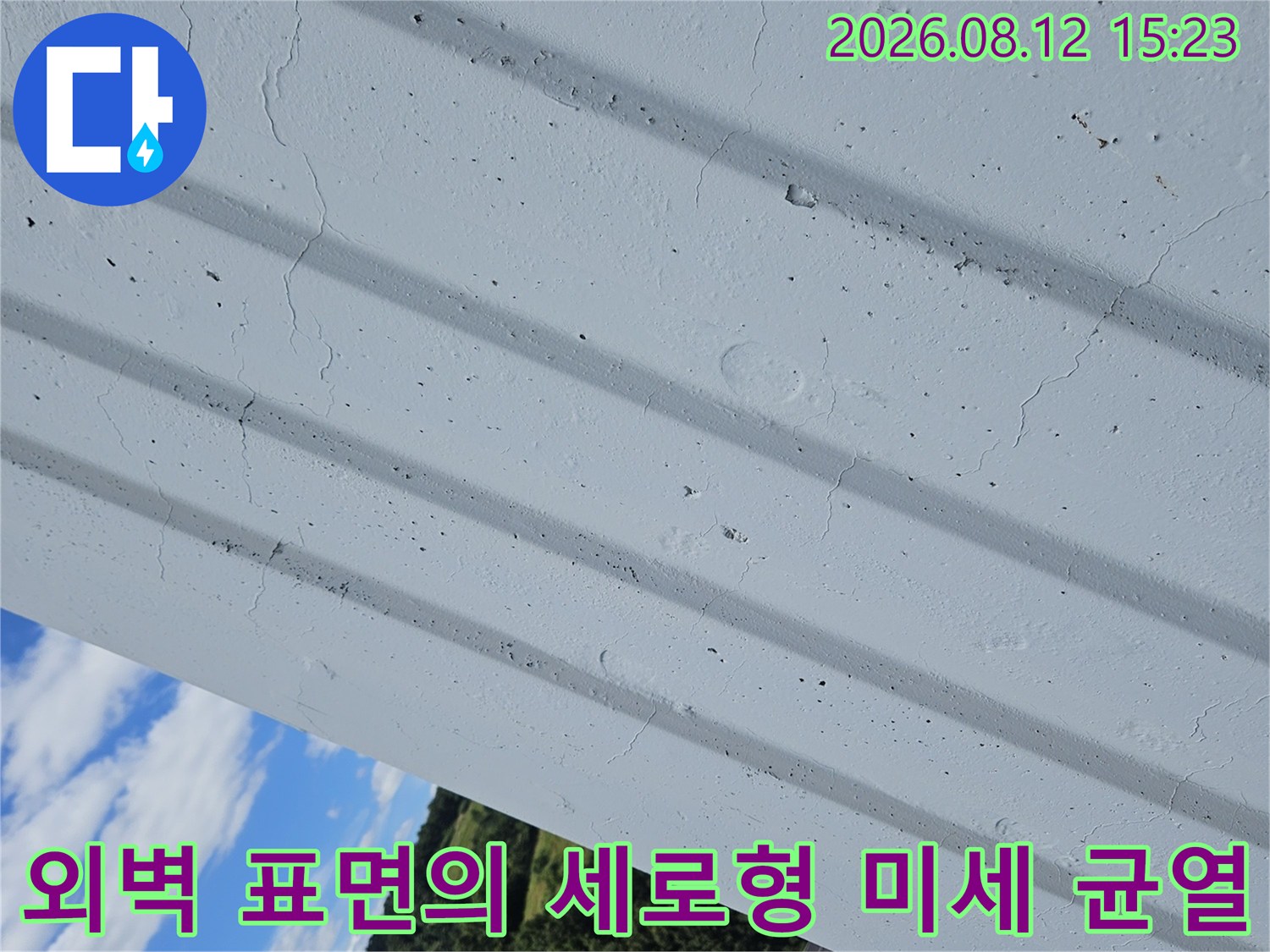 흰색 건물 외장재에 발생한 여러 줄기의 세로 방향 크랙-균열 모습
