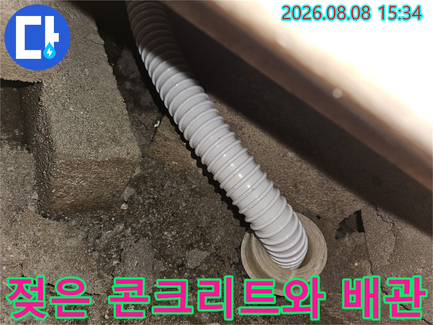 습기를 머금은 콘크리트 구조물과 연결된 하얀색 주름관 배관