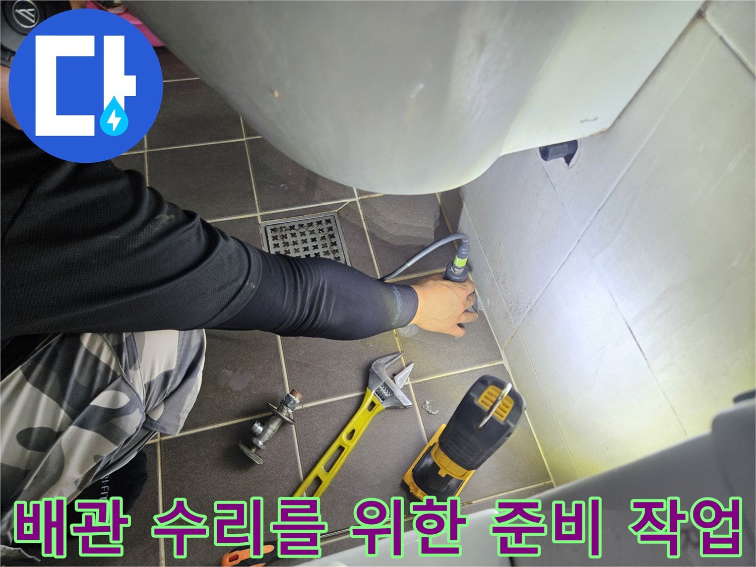 전동 드릴과 스패너를 사용하여 배관 부위를 점검하는 모습입니다.