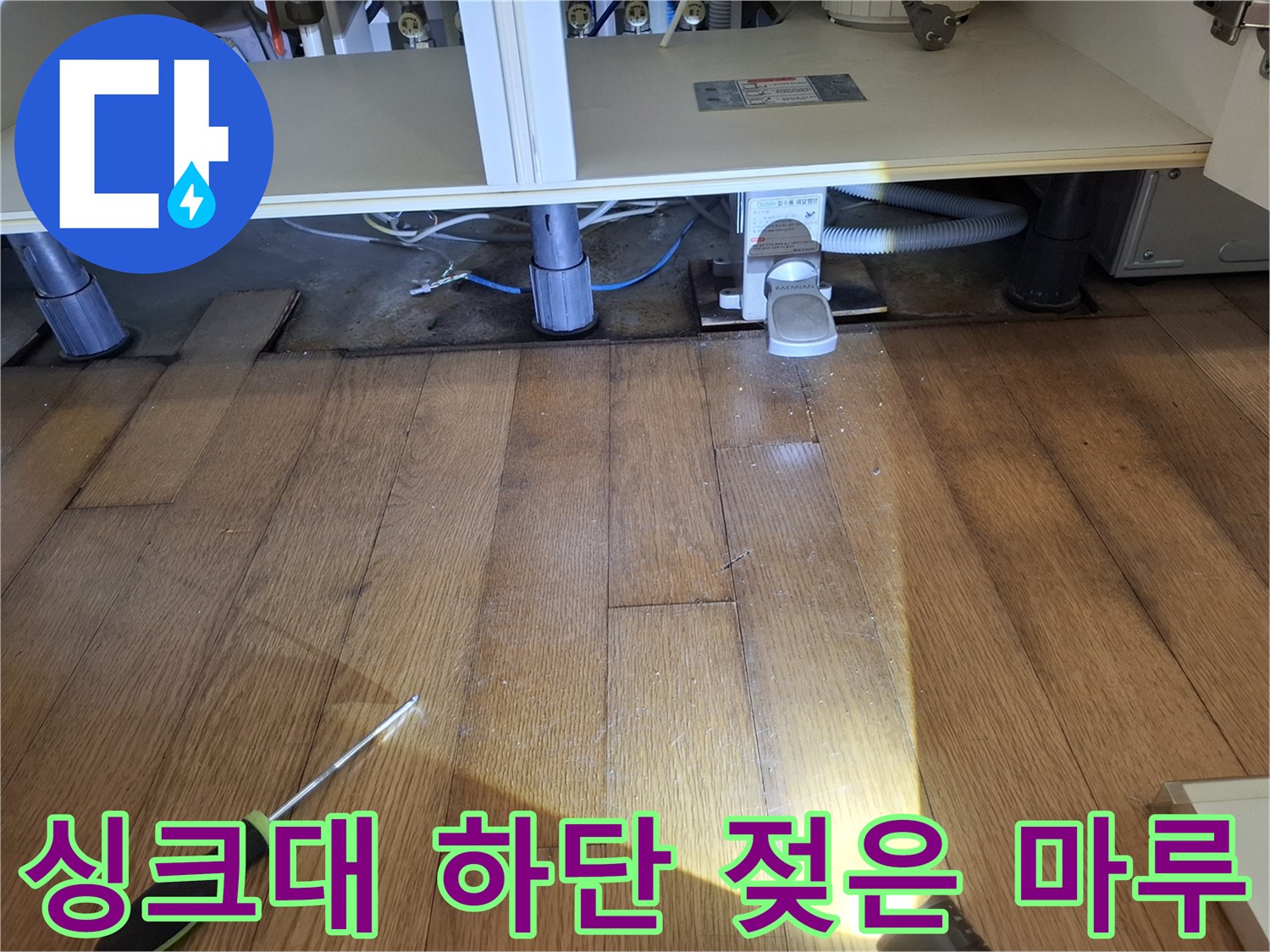 싱크대 아래쪽의 젖어 있는 강화마루와 작업 도구 사진입니다.