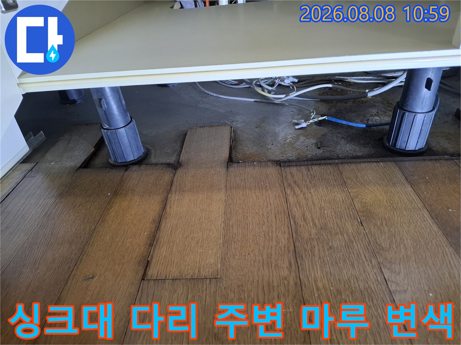 싱크대 지지대 아래쪽 마루가 젖어 어둡게 변한 상태를 촬영했습니다.