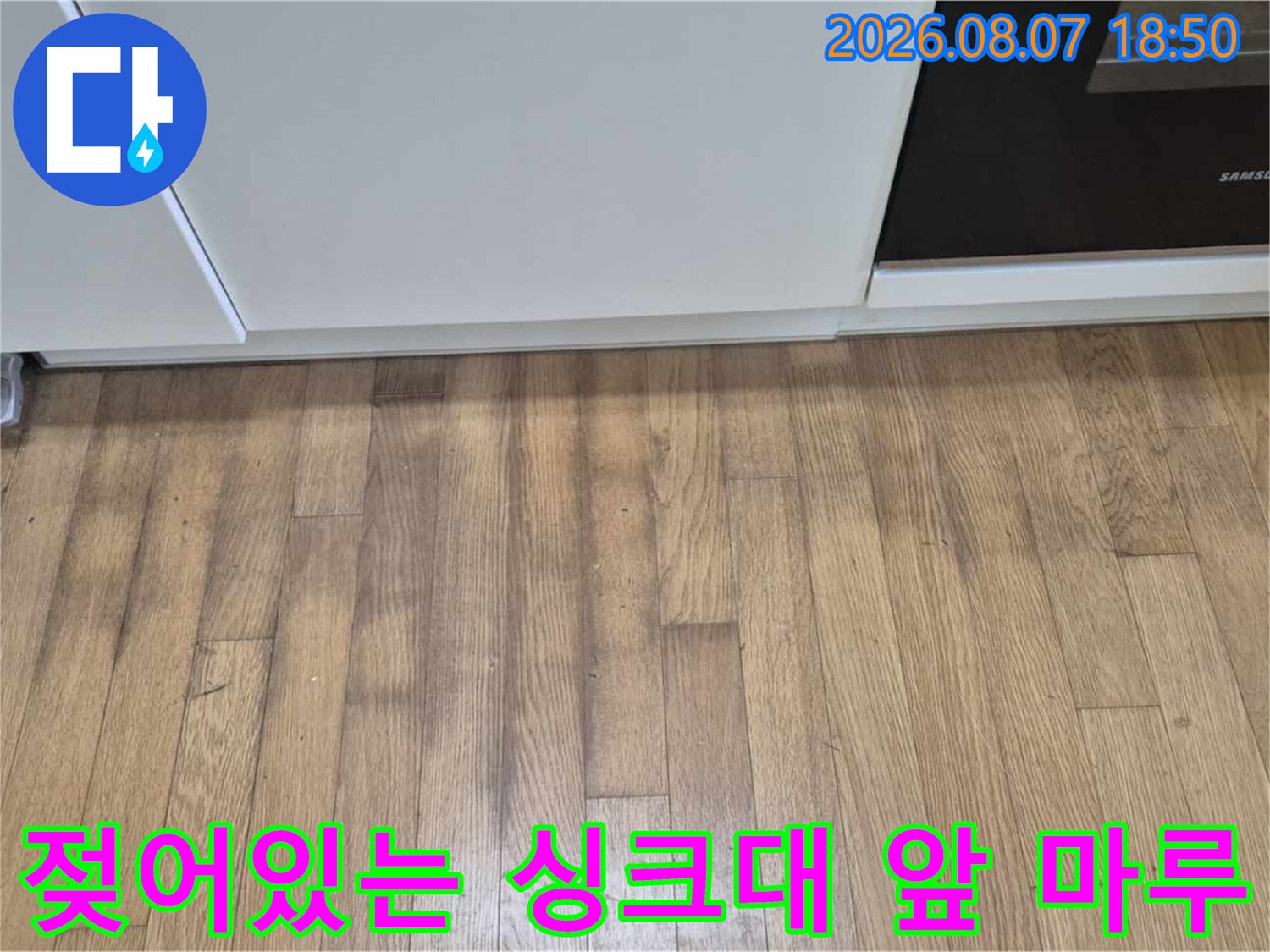 싱크대 하부장 아래쪽 마루가 물기를 머금고 어둡게 변한 모습입니다.