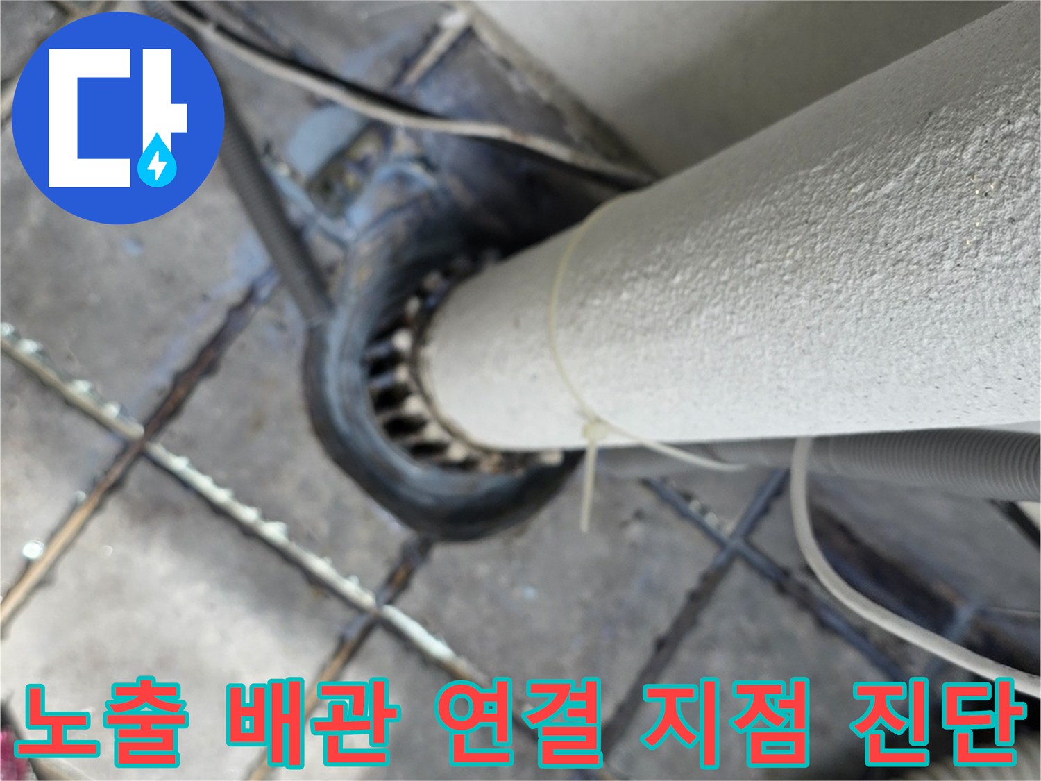 외부로 돌출된 흰색 배관과 바닥 배수구 주변의 노후 상태를 촬영했습니다.