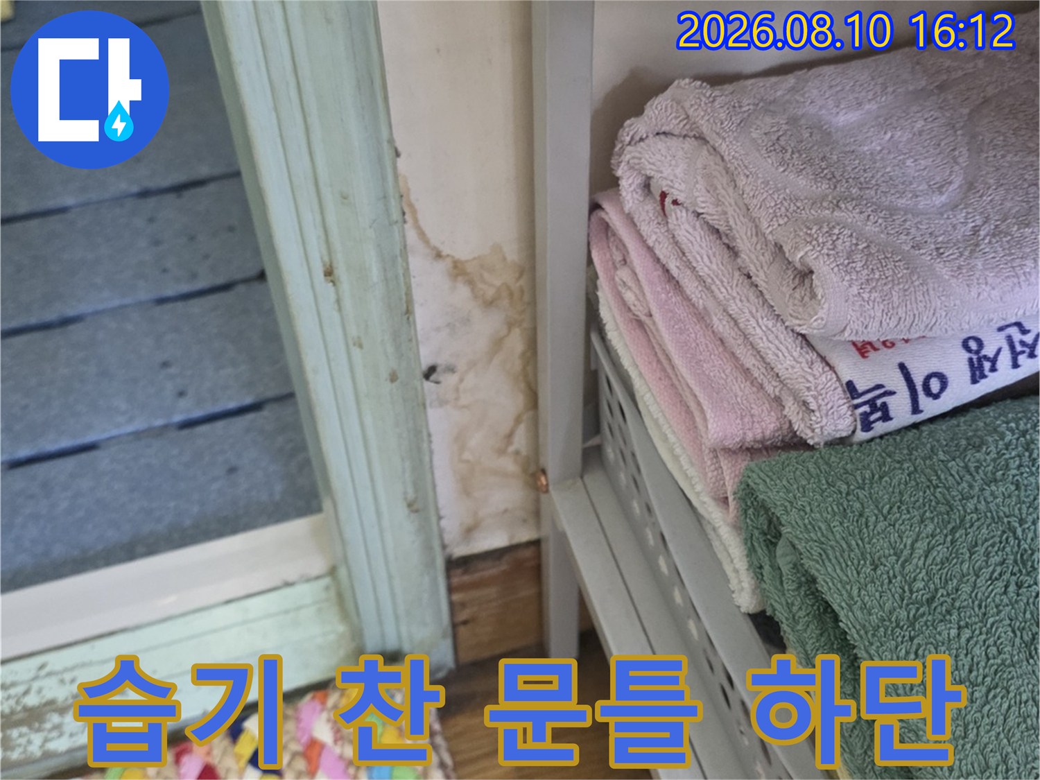 물기가 스며든-화장실 입구 문틀과 천장 마감재의 상태를 보여줍니다.