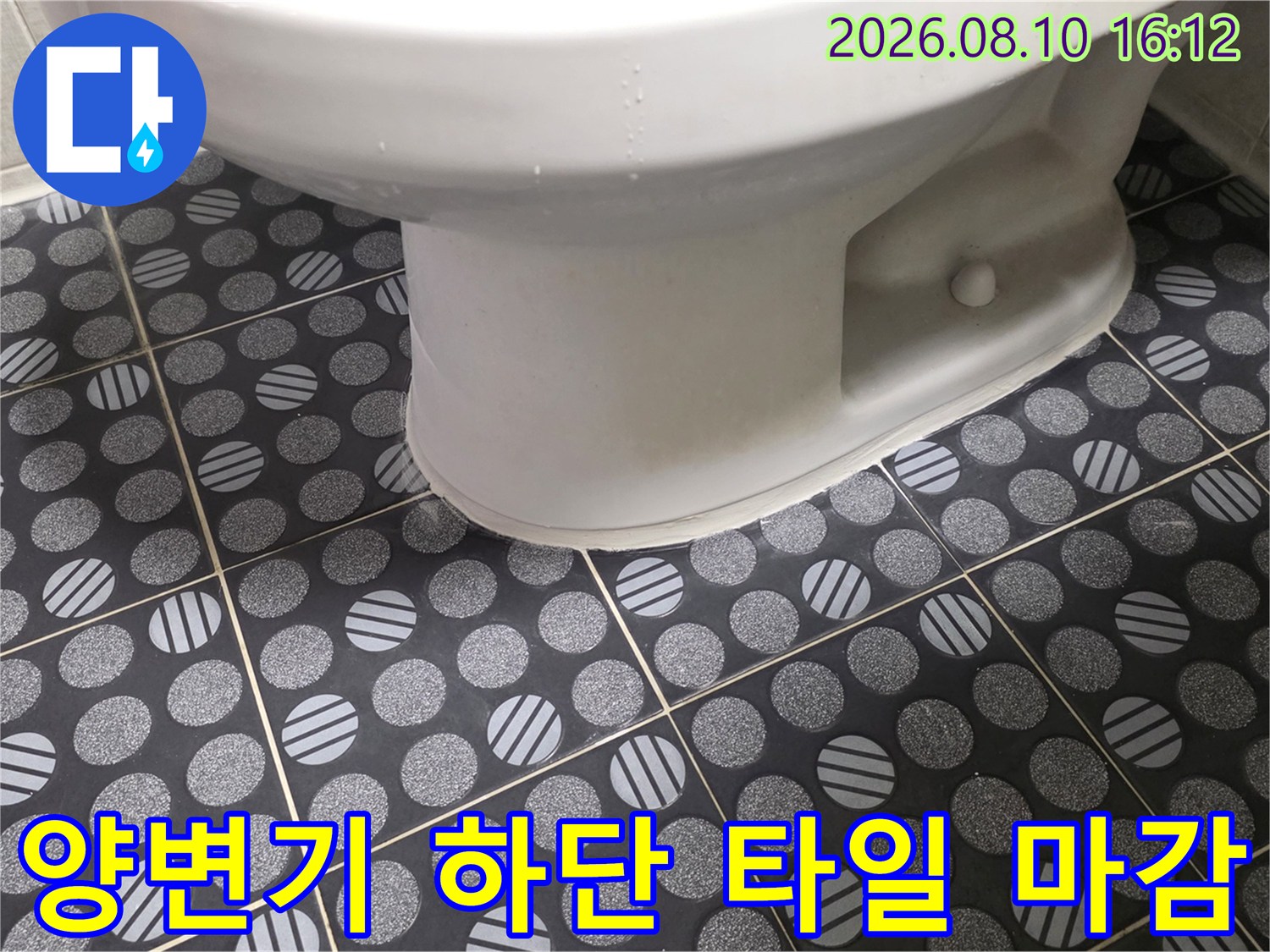 양변기 밑부분과 패턴 타일이 만나는 경계면을 촬영한 사진입니다.