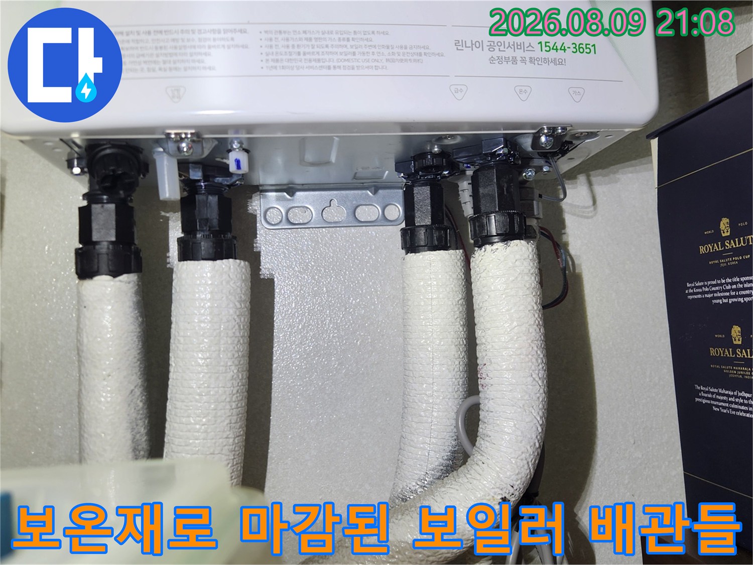 보일러 하단에 설치된 네 줄의 흰색 보온재 배관 연결 부위