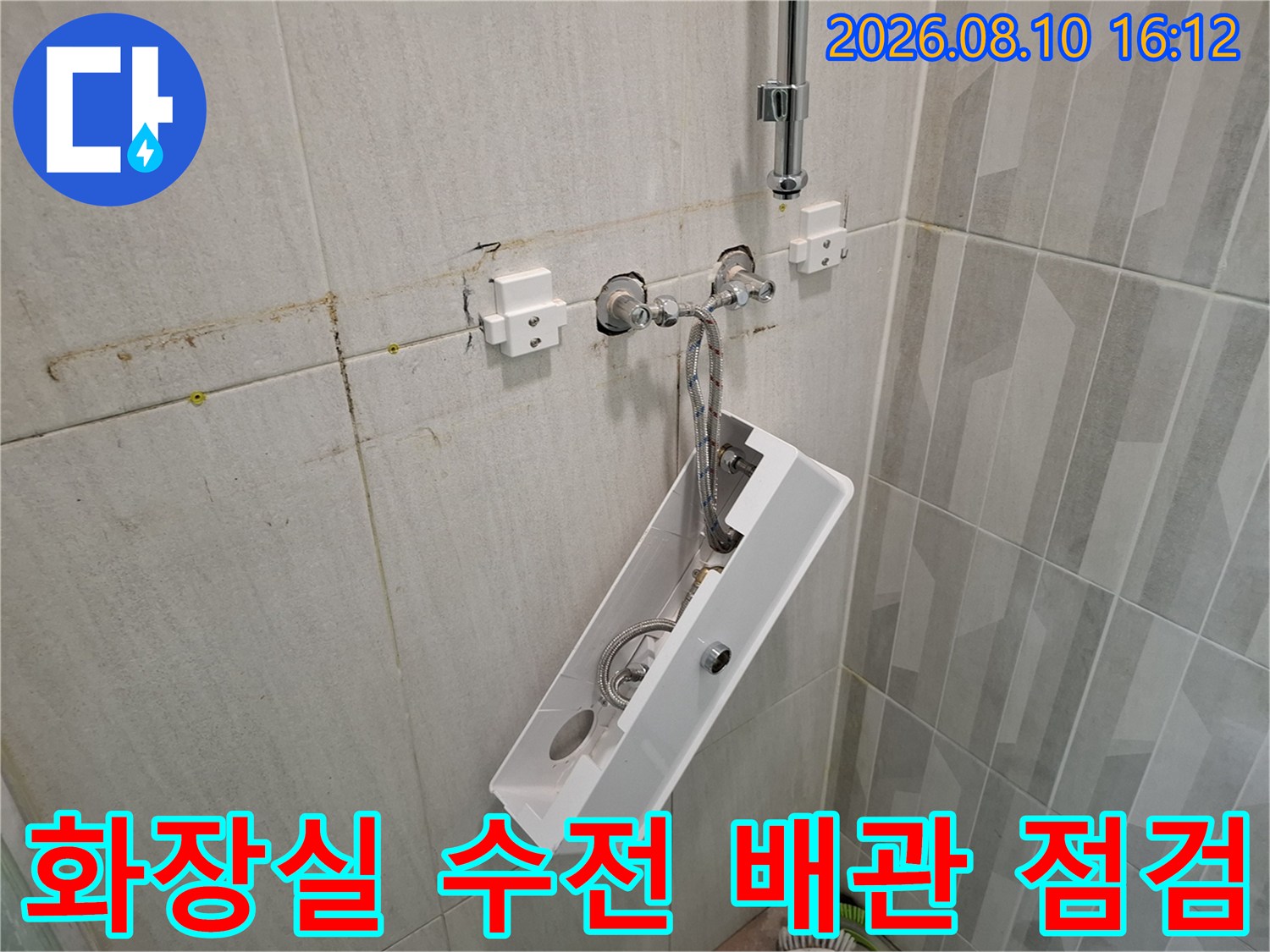 벽면 타일 균열과 함께 노출된 수전 분배기 연결부