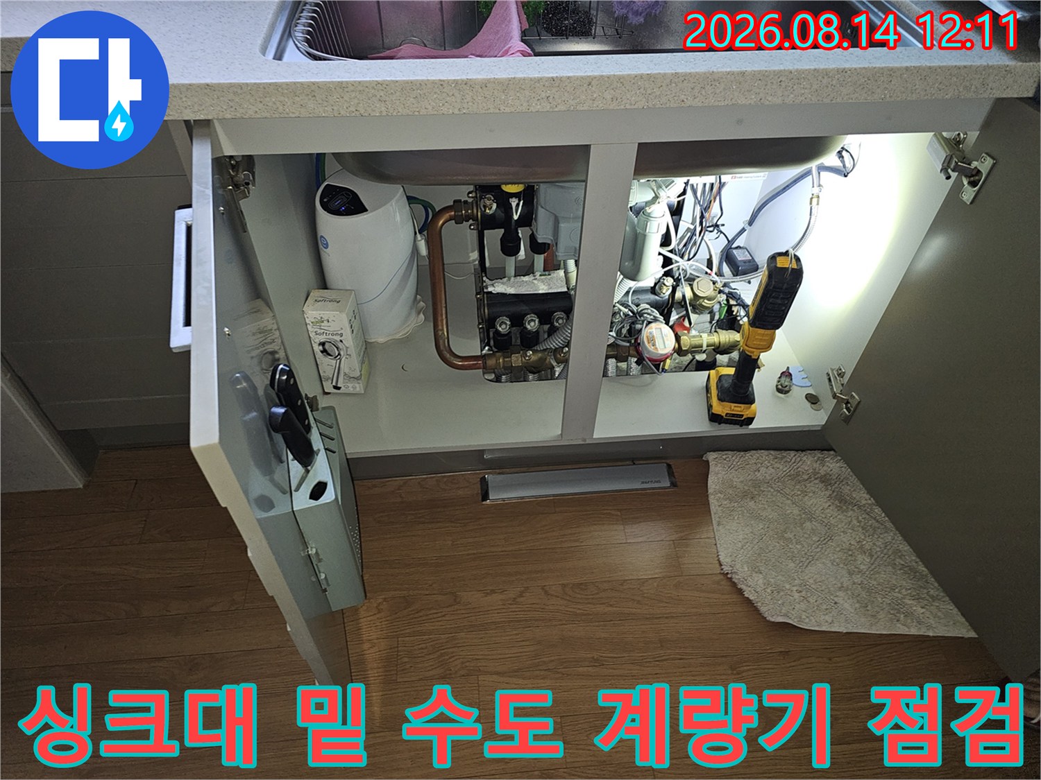 싱크대 하부장 내부의 수도 계량기와 배관 연결 부위 근접 촬영