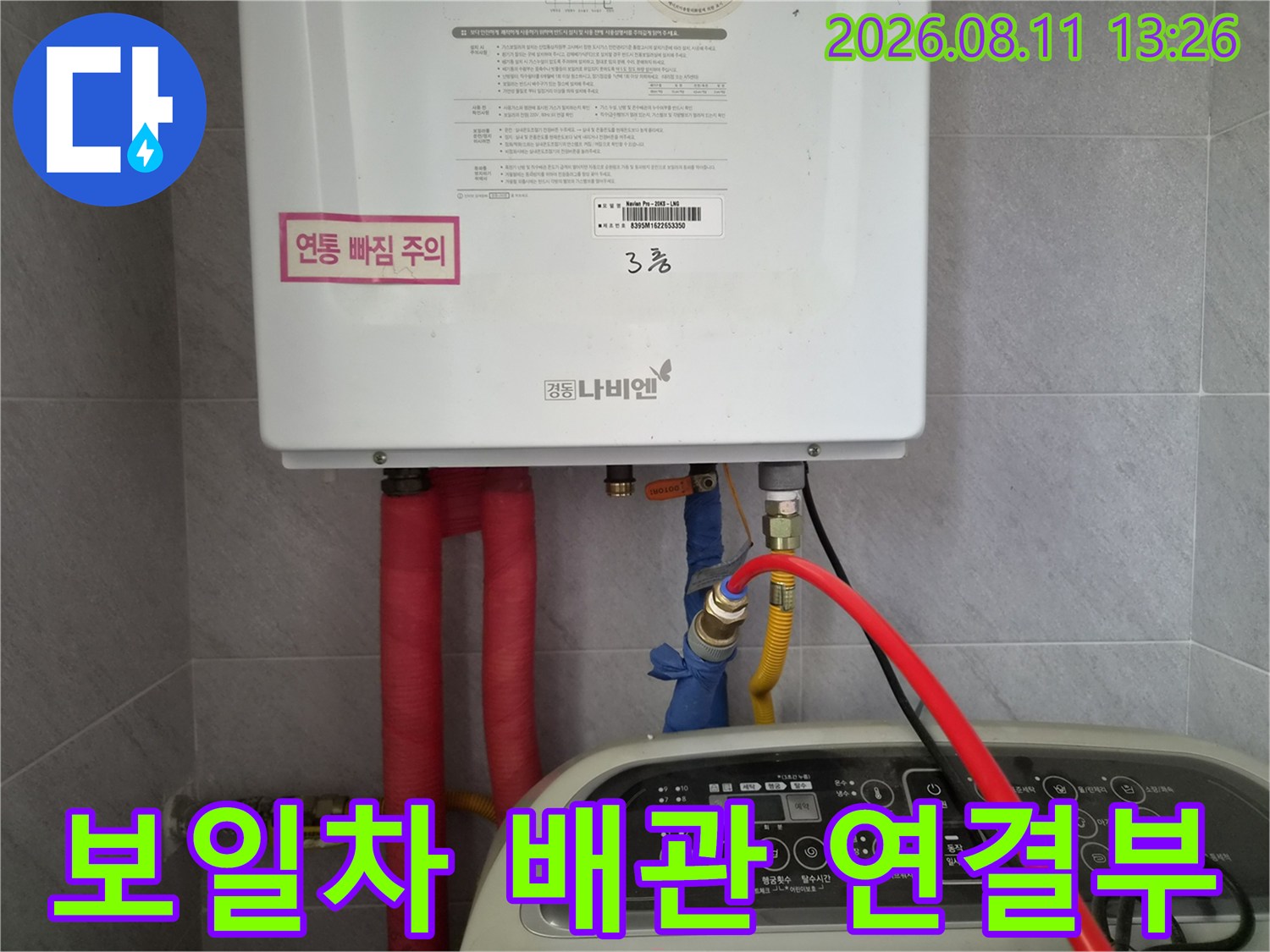 보일러 하단 배관의 밸브와 호스 연결 상태를 근접 촬영하였습니다.