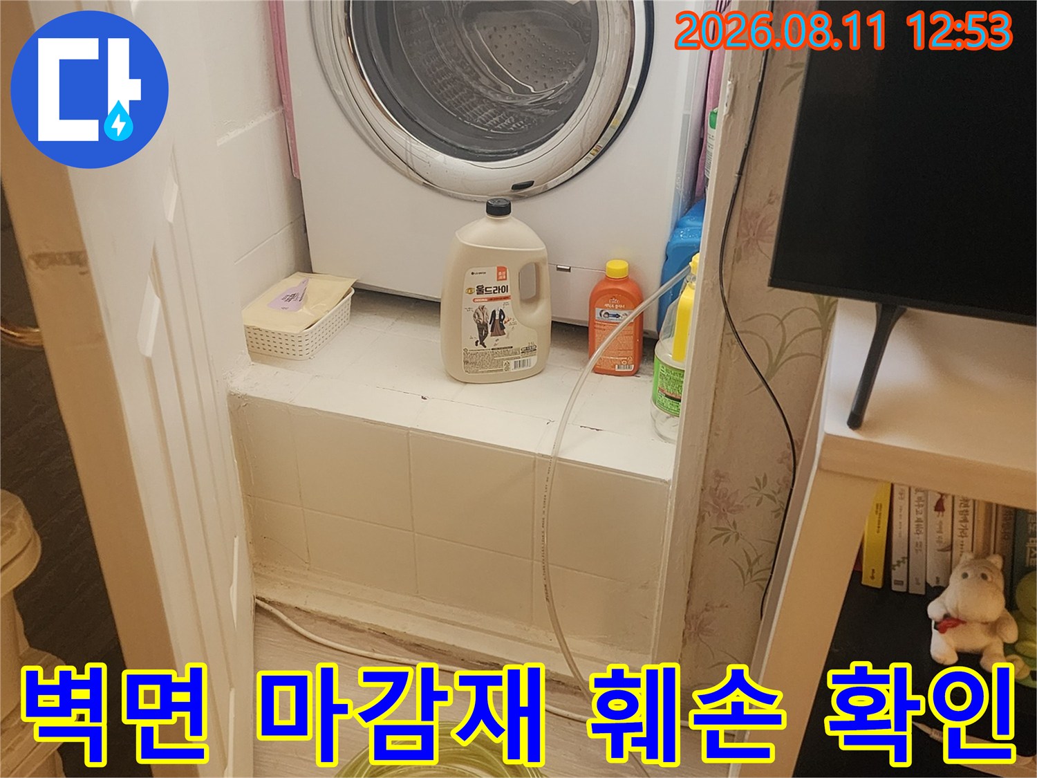 세탁기 뒤쪽 공간의 습한 벽면과 점검 도구들