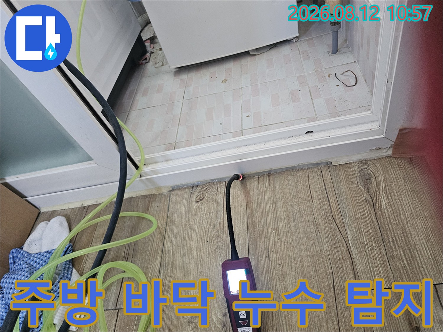 싱크대 하단 마루 부근에서-배관 누수를 찾기 위해 장비를 대고 있습니다.