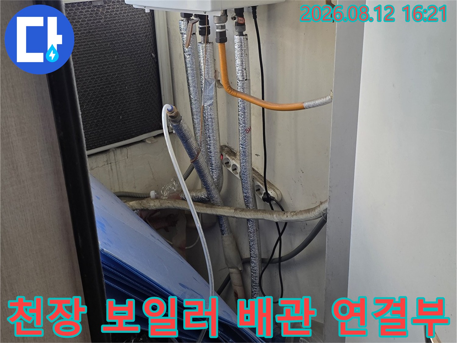 보일러 장비와 은색 주름관이 연결되어 천장 내부로 이어지는 구조 사진