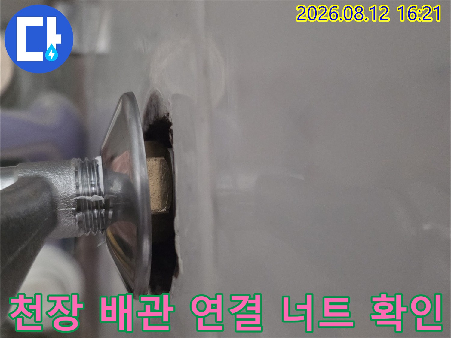 흰색 천장 마감재 사이로 노출된 은색 금속 배관-연결 부위 근접 사진