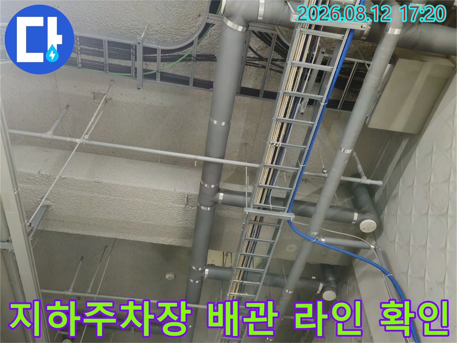 복잡하게 얽힌 지하주차장 천장의 회색 배관과 전기 트레이 구조물