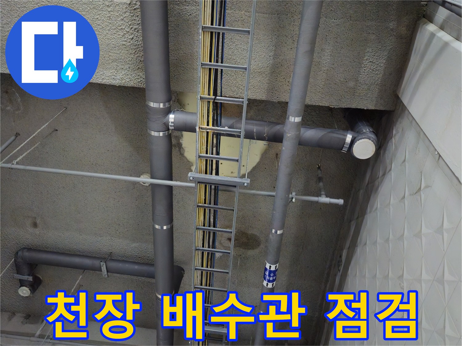 상가 주차장 천장에 설치된 회색 배수관과 전선 트레이 구조물
