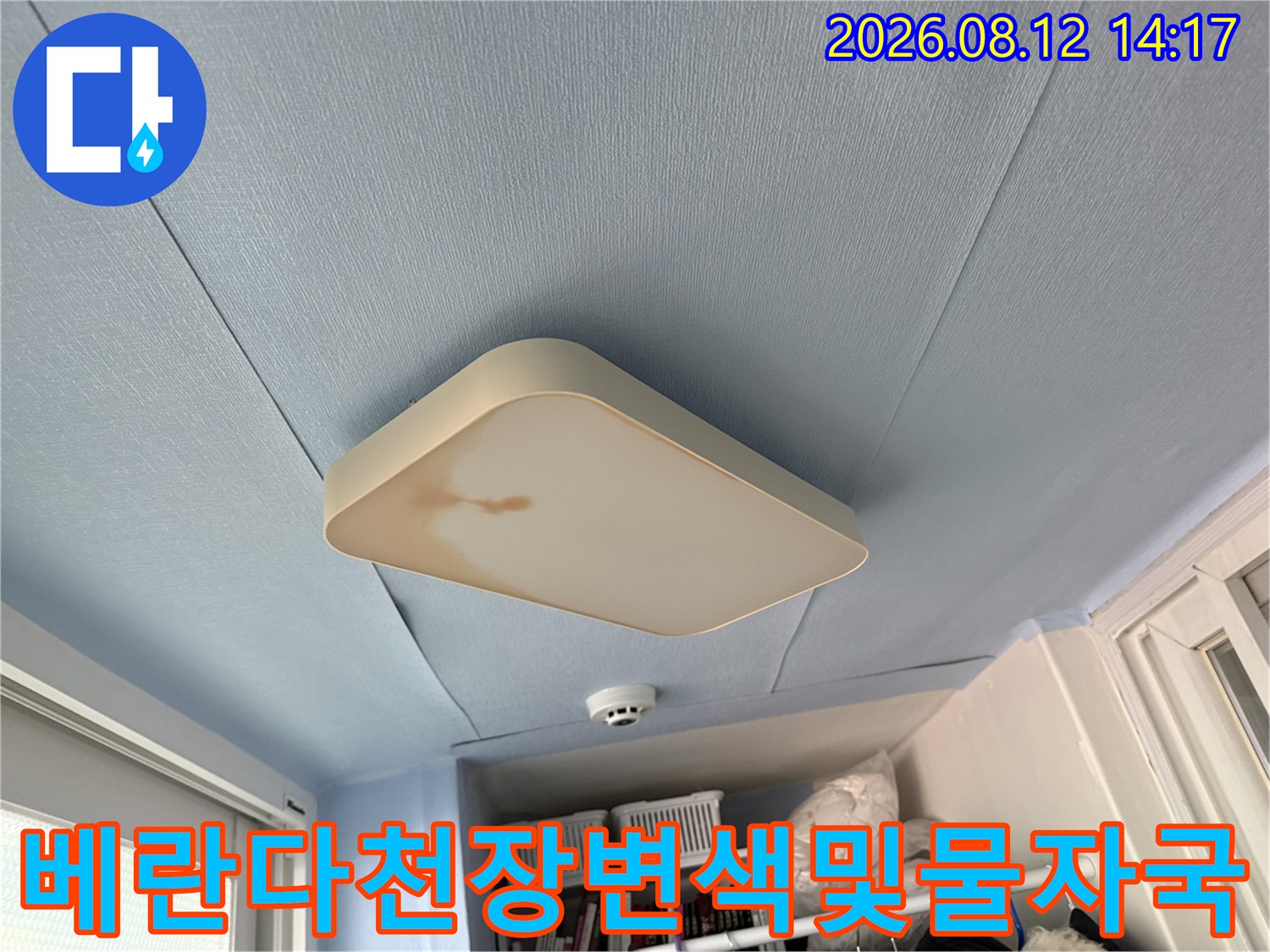 푸른색 베란다 천장의 사각 조명 기구 왼쪽에 갈색의 누수 오염물이 묻어 있는 모습