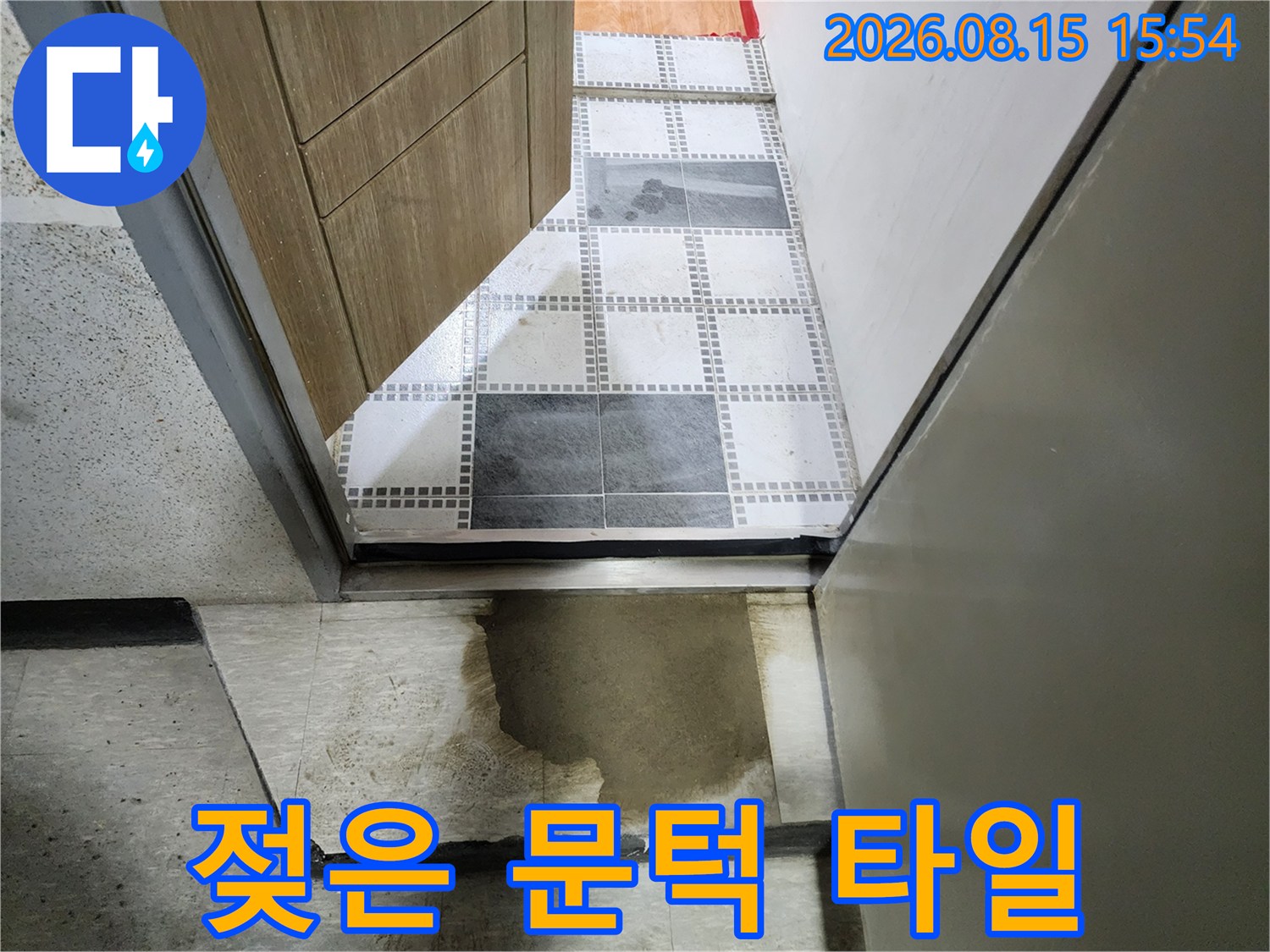 문턱 주변 타일의 짙게 변한 습기 얼룩
