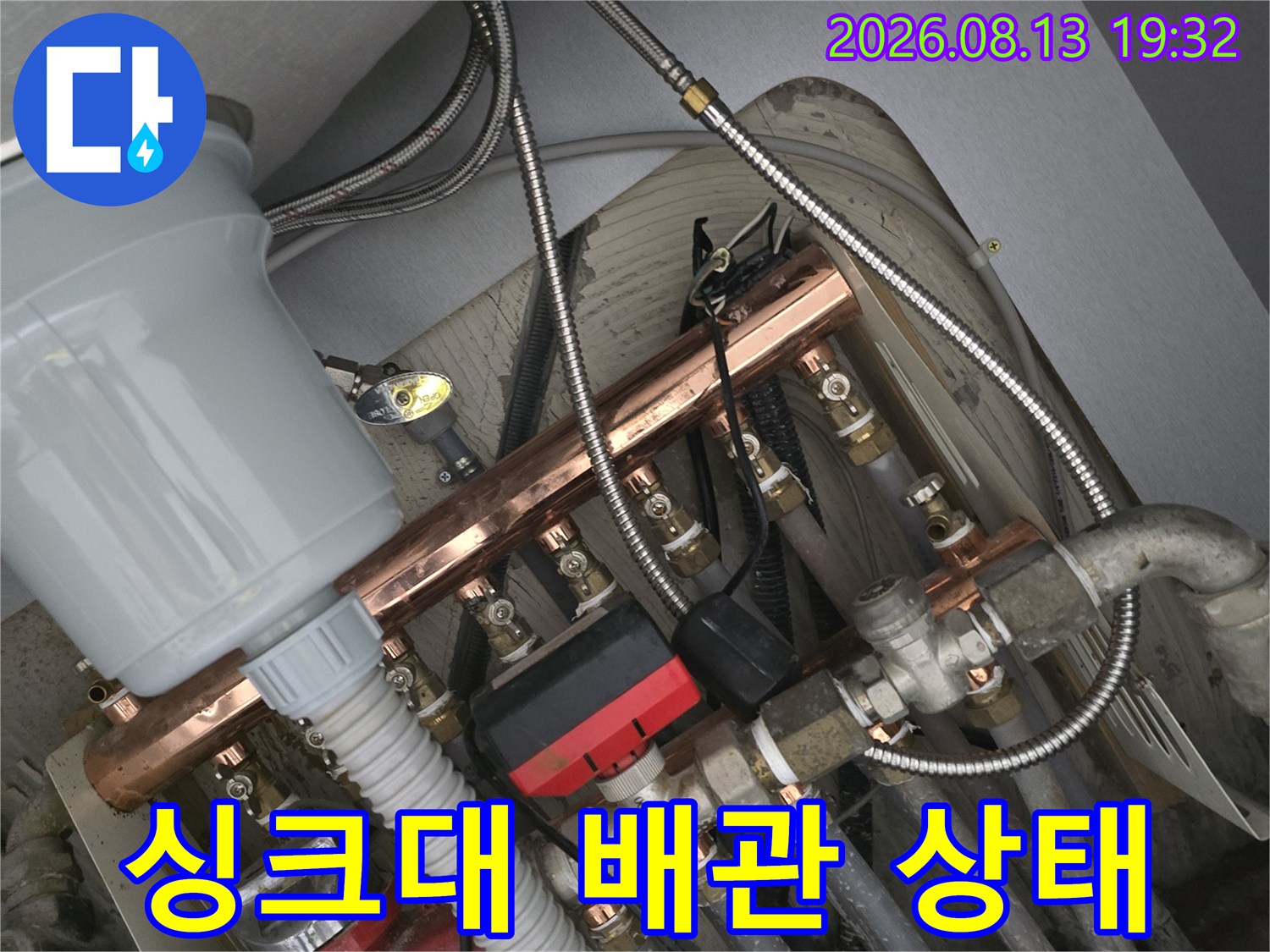 싱크대 하부장 내부의 금속 분배기와 급수 호스 연결 모습