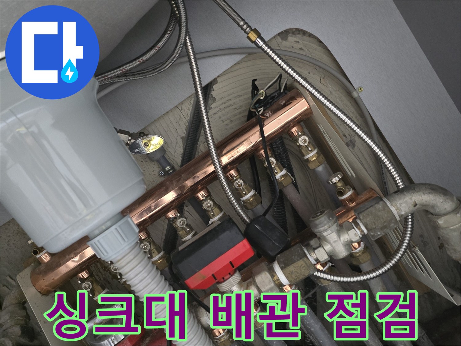 주방 싱크대 아래쪽의 복잡한 급수 배관과 연결 부위 모습입니다.