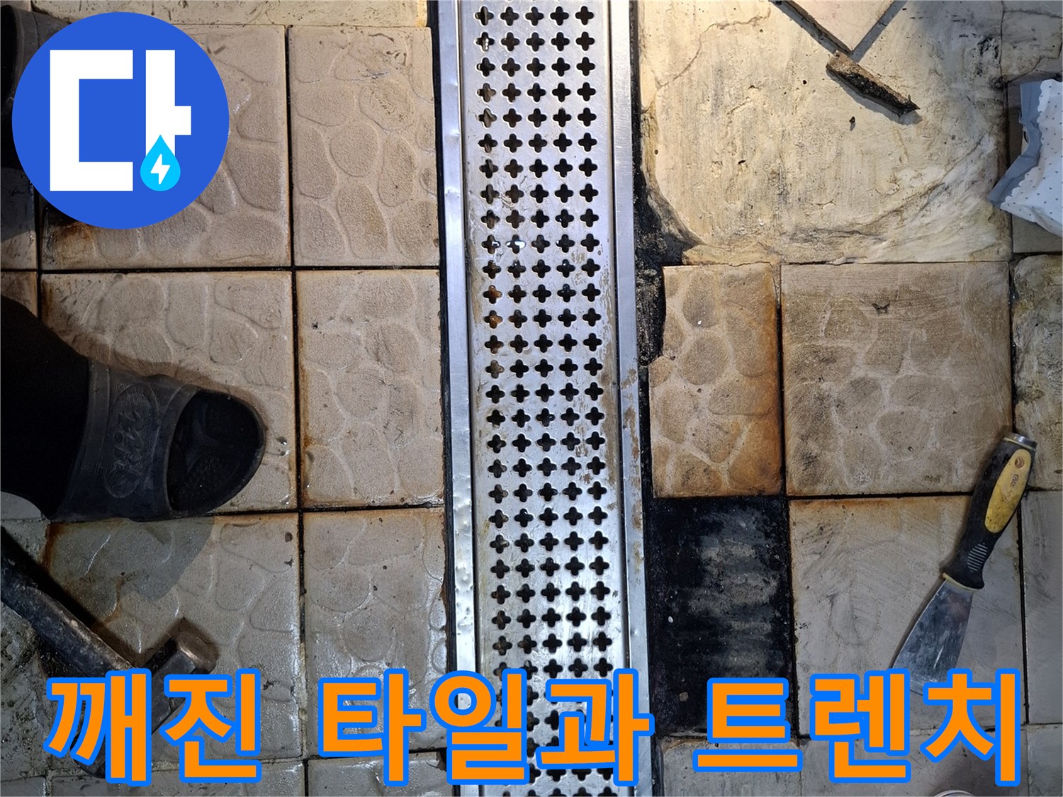 금속 배수 트렌치 주변의 깨진 타일과 오염된 바닥