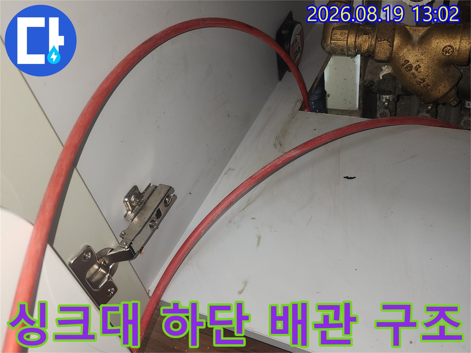 싱크대 밑 밸브와 연결된 붉은색 호스의 모습